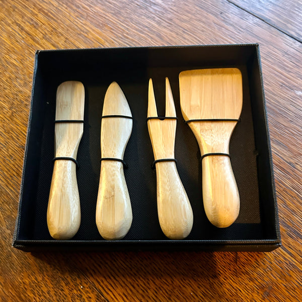 Set of four wooden cheese knives in a black box on a wooden surface