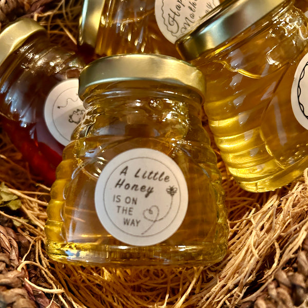 Three jars of honey with labels on a woven background