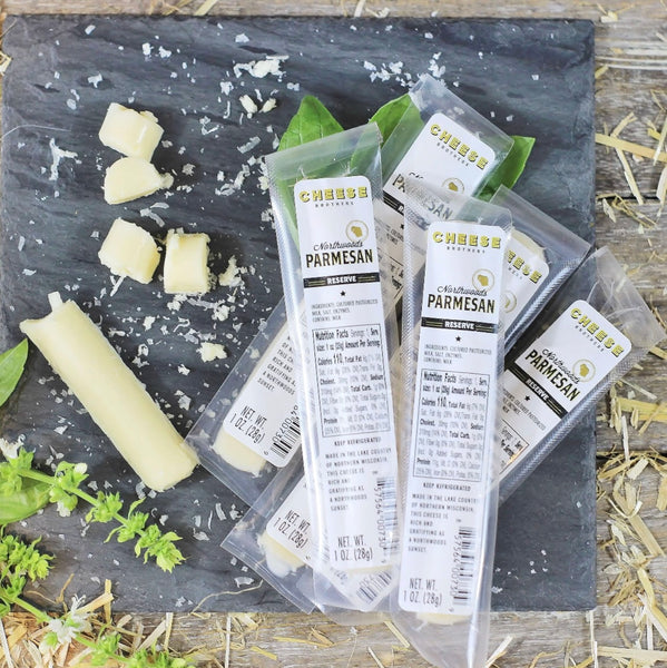 Packaged Parmesan cheese on a wooden surface with cheese shavings and leaves.