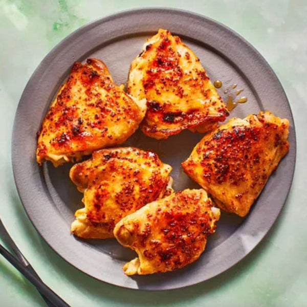 Baked chicken thighs on a gray plate with a light green background