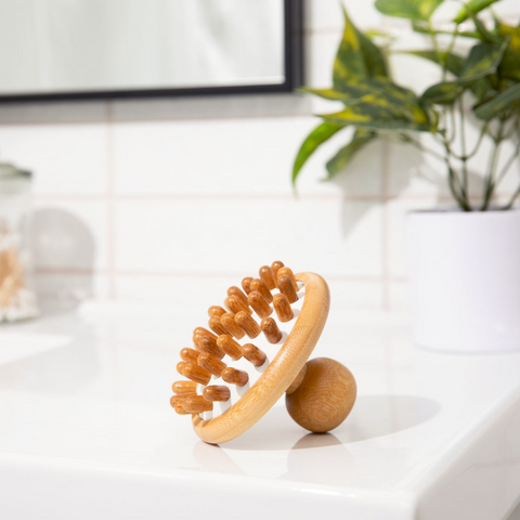 A Bamboo Stimulating Scalp Massager on the side of a sink